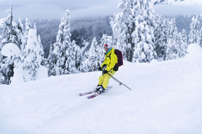 Woman in yellow backcountry skiing in squamish, bc, paul's ridge