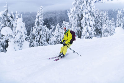 Person skiing on snowcapped mountain during winter