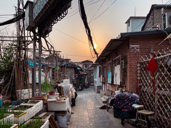 People on street amidst buildings in city during sunset