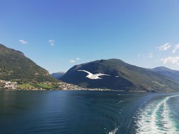 Scenic view of sea and mountains against blue sky