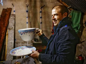 Happy man holding large tea cup and saucer at home