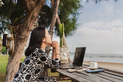 Business woman relaxing breathing fresh air while working with computer on the beach.