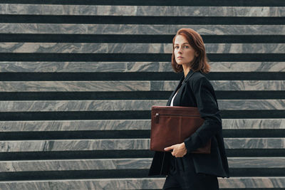 Young woman standing against wall