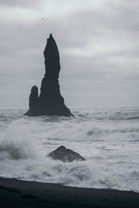 Rock formation on sea shore against sky