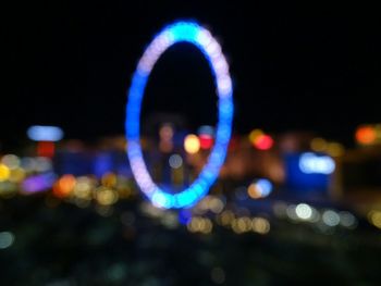 Illuminated blurred ferris wheel against dark sky