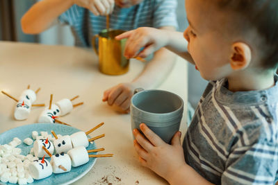 Cute brothers decorating marshmallows at home