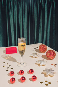 New year party composition with jewelry box, champagne glass, confetti and red christmas baubles. 