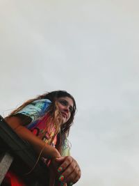 Low angle view of young woman  against sky 