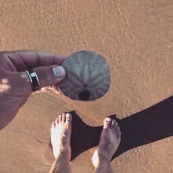 Low section of woman with shadow on sand