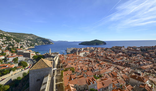 Aerial view of townscape by sea against sky