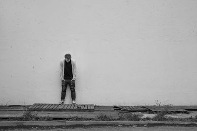 Young man looking down while standing against wall