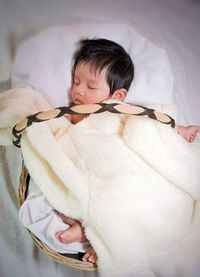 High angle view of baby girl sleeping in moses basket