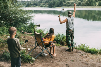 A young man teaches his children to fish during a family vacation at a camping site. hobbies