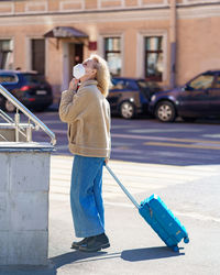 Senior 60s woman with blue suitcase traveling alone during coronavirus epidemic