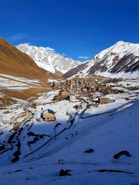 Aerial view of snowcapped mountains against blue sky