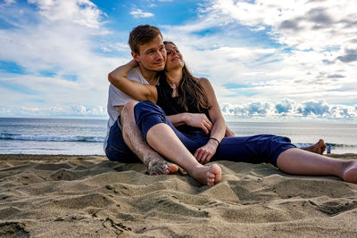 Happy friends enjoying at beach against sky