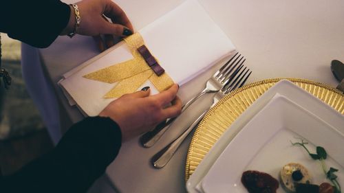 Cropped hands of woman arranging napkin on table