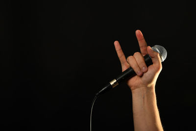 Cropped image of man holding headphones over black background