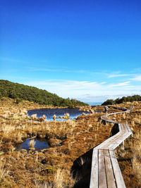 Boardwalk by pond against sky