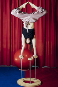 Female performer stretching legs while doing handstand at circus