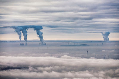 Smoke emitting from chimney against sky, low clouds covering the city of düsseldorf