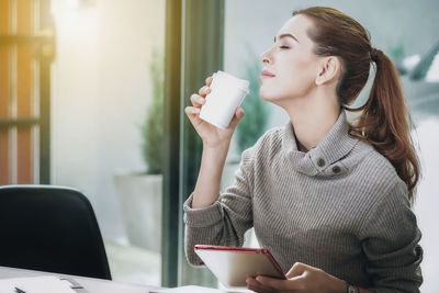 Young woman using mobile phone while sitting on table