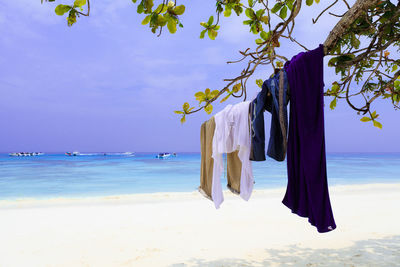 Clothes drying on beach by sea against sky