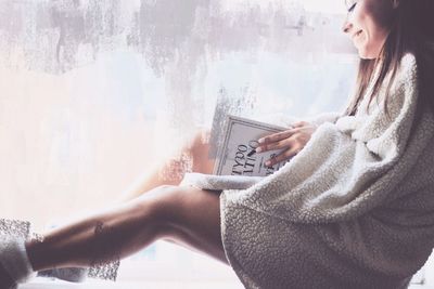 Double exposure image of smiling woman reading book and wall