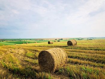 Hay bales on field against sky