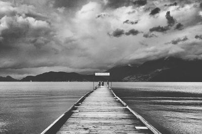 Pier on sea against cloudy sky