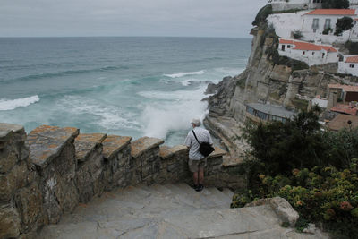 High angle view of senior man standing on staircase against sea