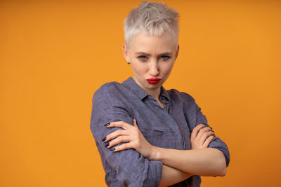 Portrait of young woman puckering against orange background