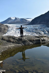 Rear view of man standing by lake against sky