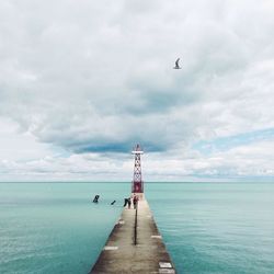 Pier on sea against cloudy sky