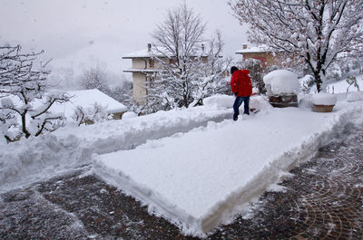 Rear view of man walking on snow covered buildings