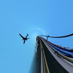 Little planet effect of airplane and rollercoaster against clear blue sky