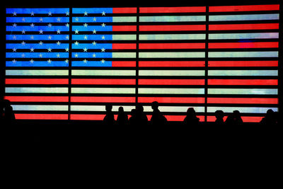 Silhouette people against illuminated american flag
