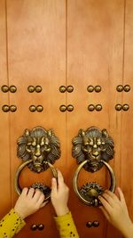 Cropped hands holding metallic door knockers