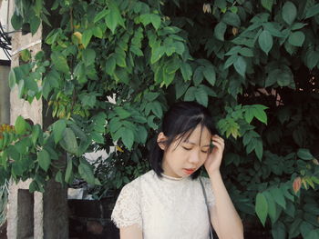 Young woman standing against plants