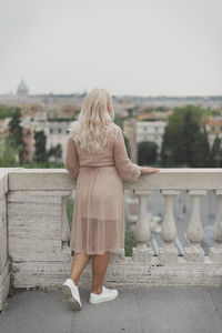 Rear view of woman standing against railing