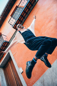 Low angle view of young man jumping against wall