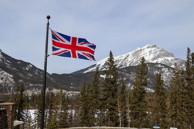 Low angle view of flag on snowcapped mountain against sky