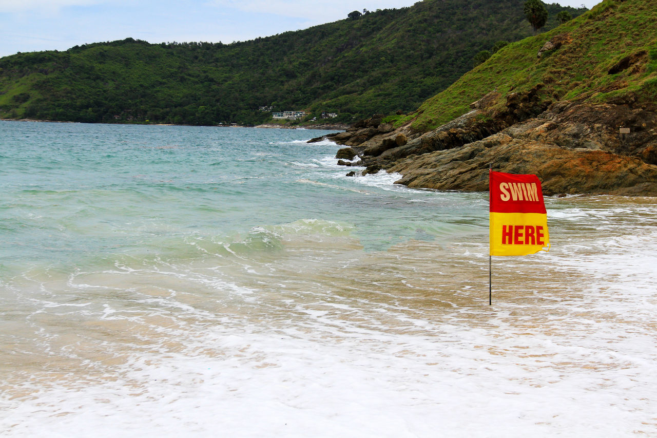 SIGN ON BEACH AGAINST SKY