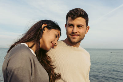 Portrait of young couple by sea against sky