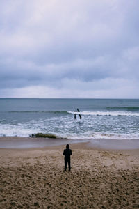 Rear view of men on beach against sky