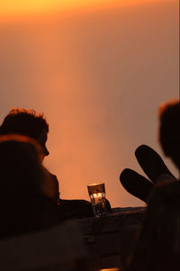 Silhouette man drinking beer glass against sunset sky