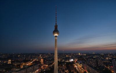 Communications tower in city against clear sky at night