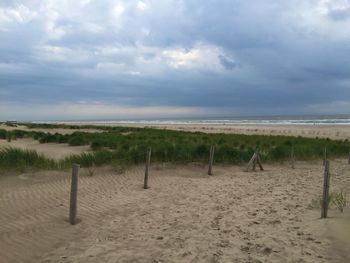 Scenic view of beach against cloudy sky