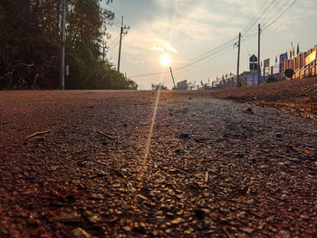 Surface level of road against sky during sunset