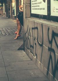 Low section of woman sitting at sidewalk in city